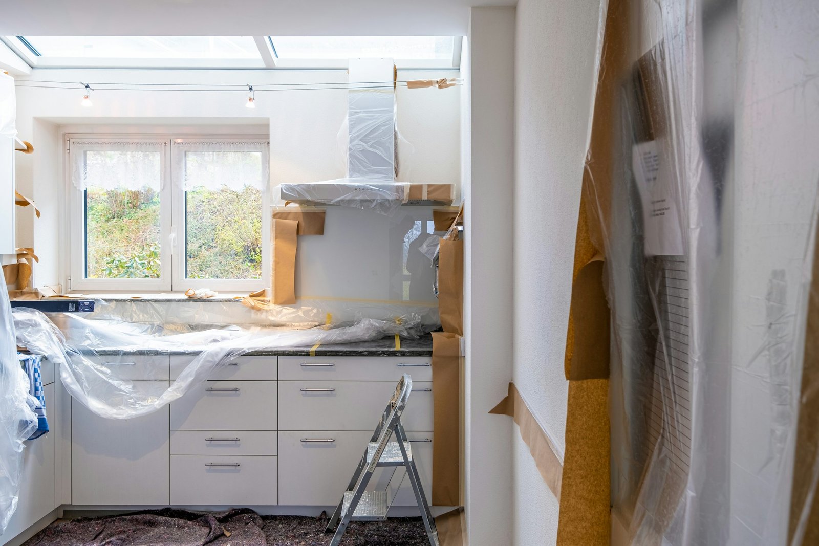Kitchen renovation with brown masking paper and plastic covering cabinets and fixtures